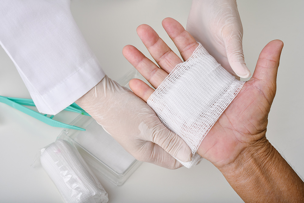 Doctor doing wound dressing care and bandaging patient's hand